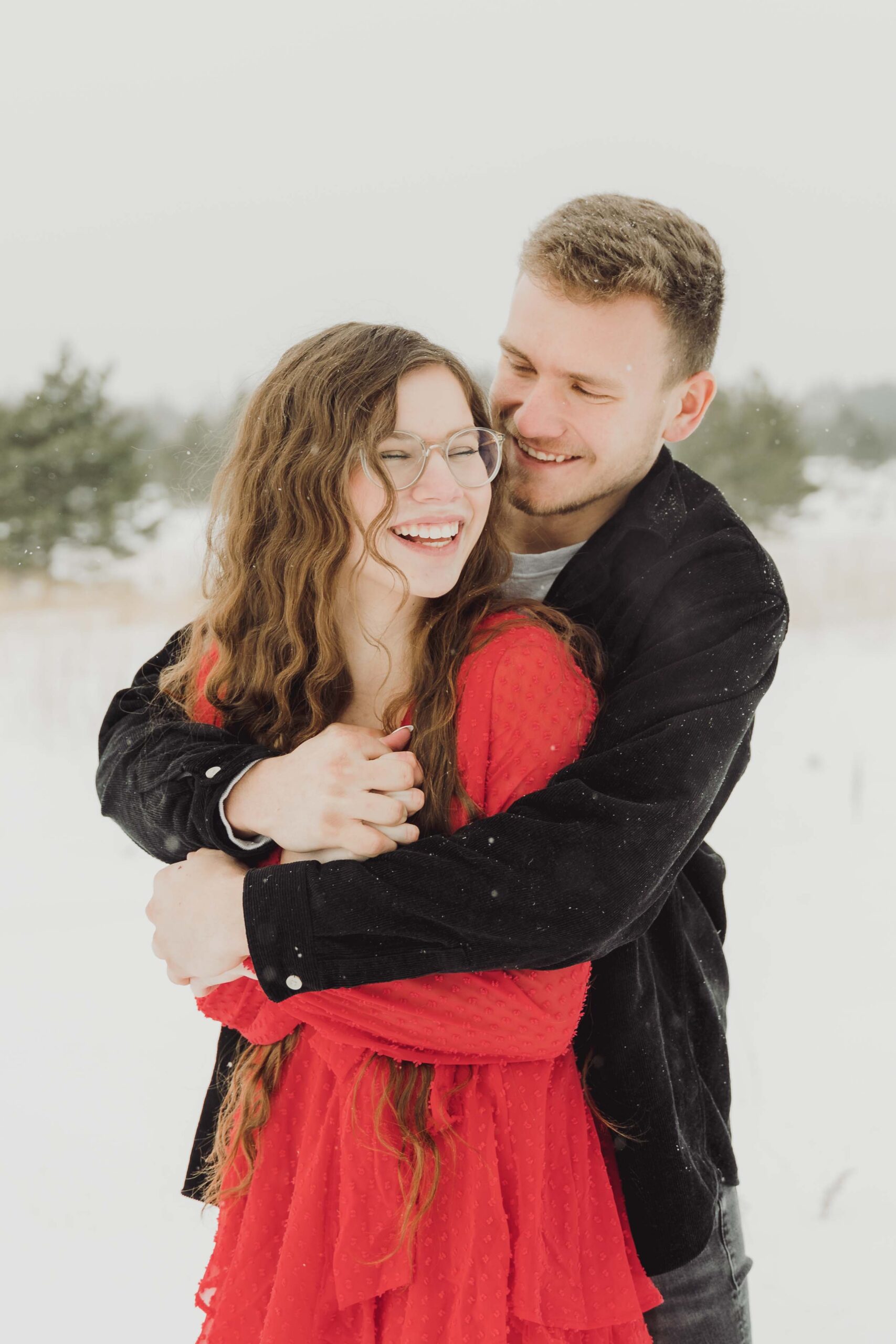 Couple hugging during their snowy winter engagement session